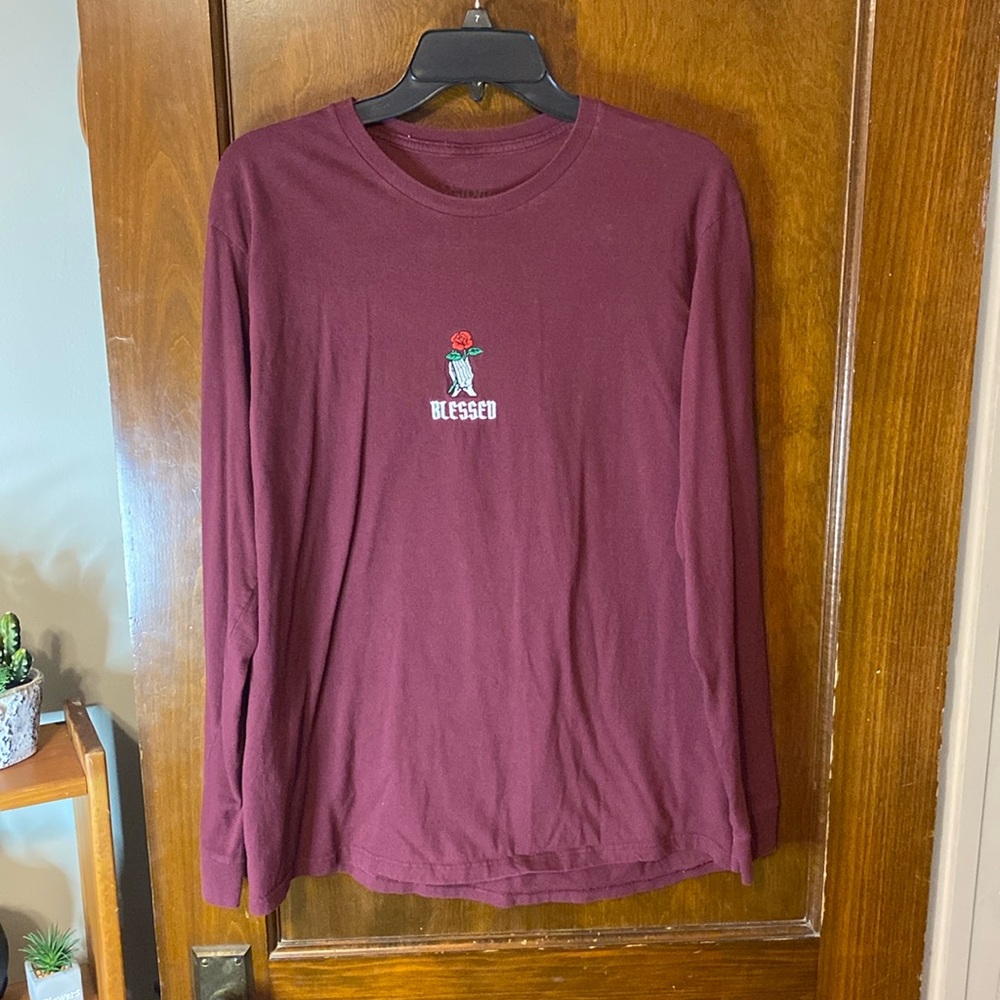 SKELETON HANDS HOLDING A ROSE LOGO THAT SAYS “BLESSED” ON A BURGUNDY LONG SLEEVE